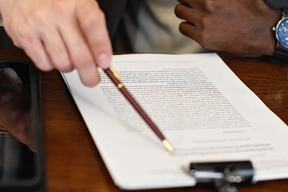 Mão aponta uma linha do contrato durante o atendimento