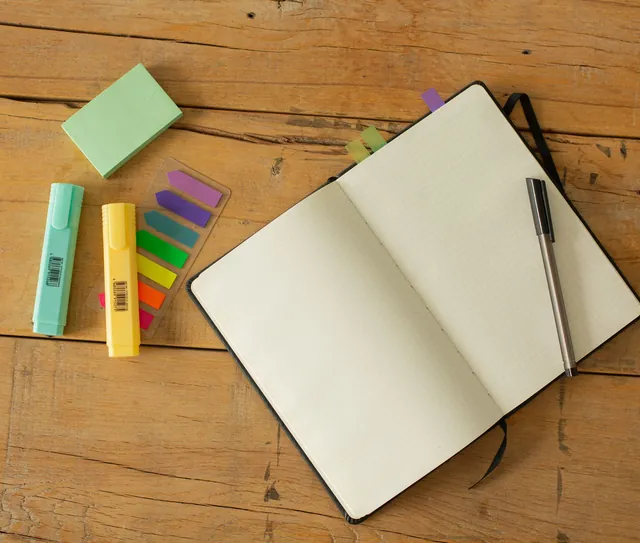 Caderno aberto, marcadores e caneta sobre a mesa