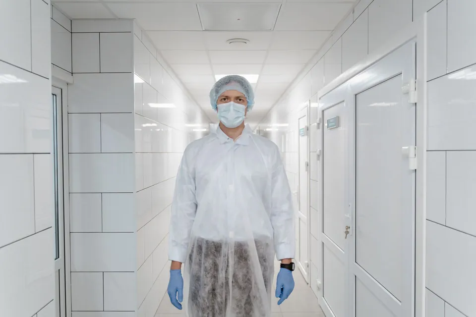 Profissional de uniforme e máscara em corredor de trabalho