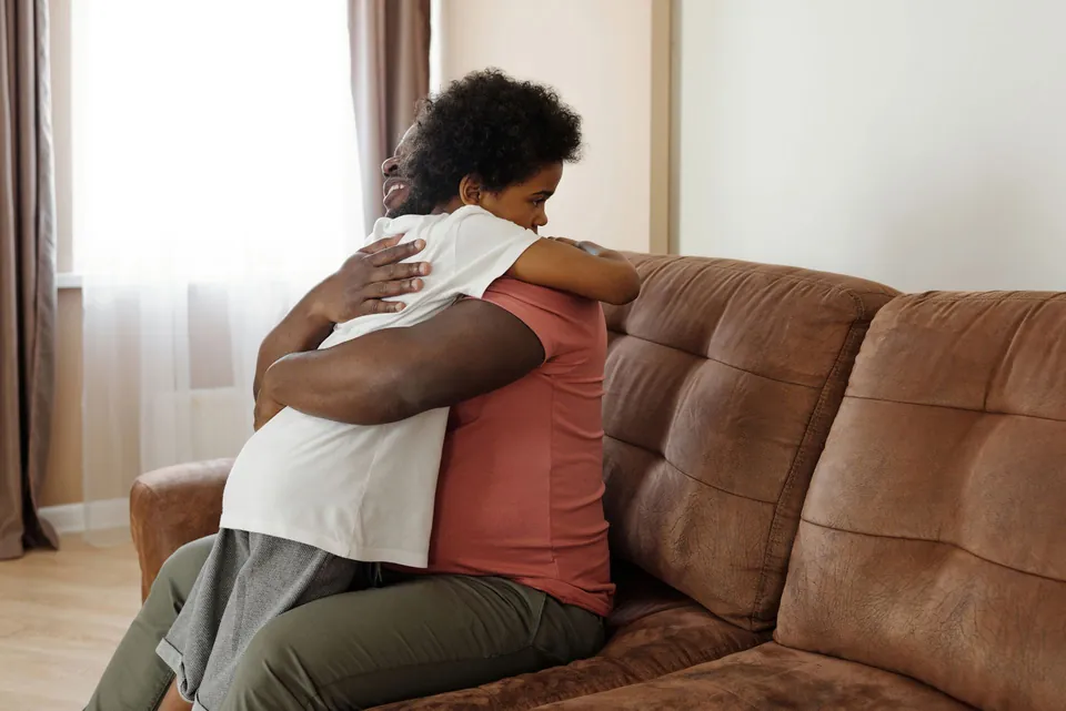 Criança abraça o pai no sofá de casa
