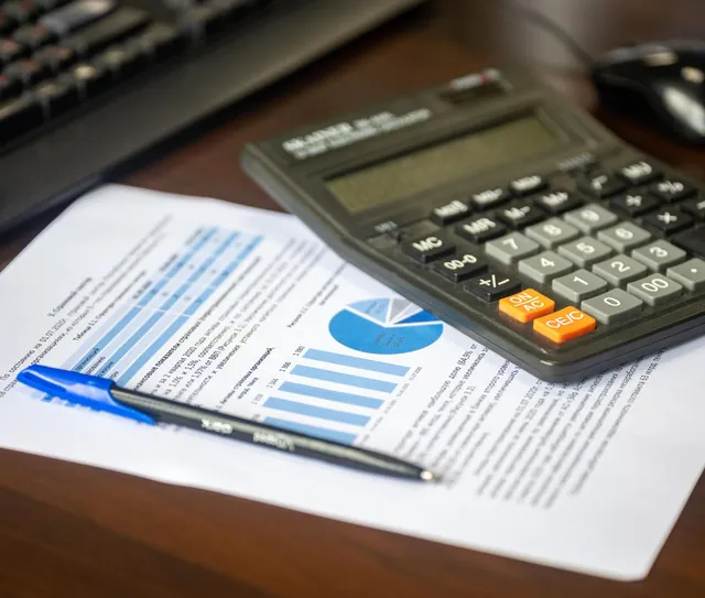 Calculadora e caneta sobre um documento impresso, na mesa de trabalho