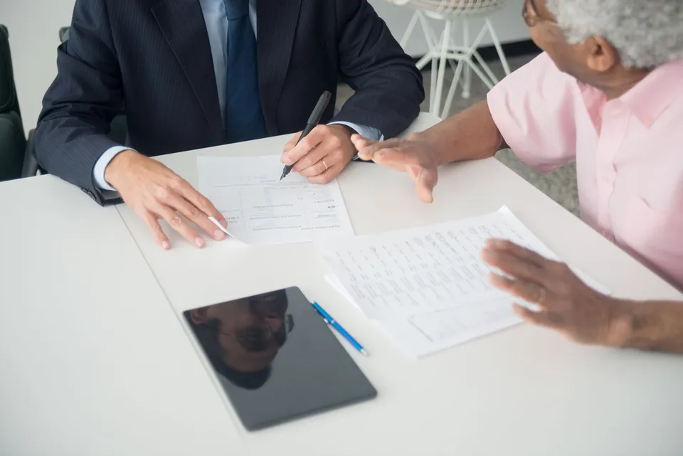 Profissional conversa com um cliente idoso sobre documentos