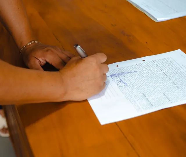 Mãos assinam um documento sobre a mesa de madeira