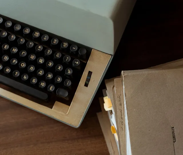 Máquina de escrever antiga ao lado de pastas de papel