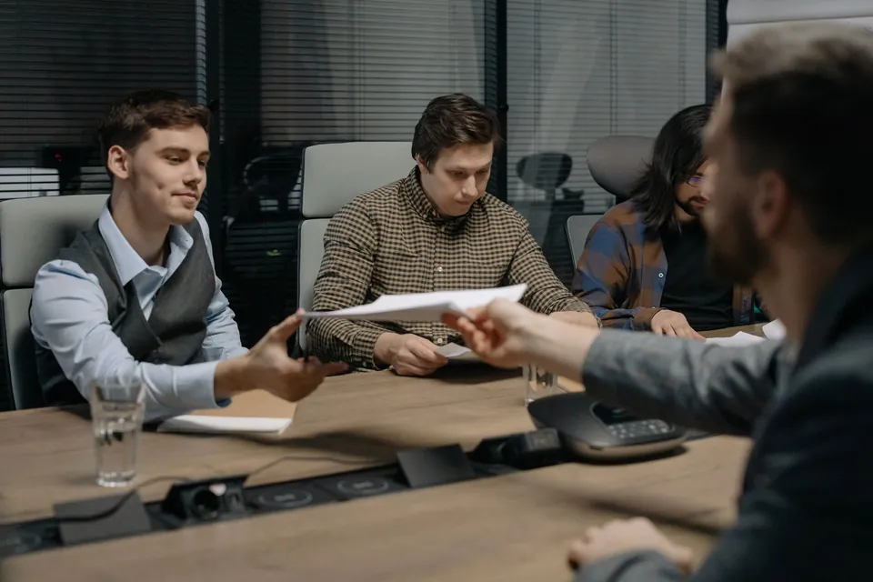 Profissionais trocam documentos em uma reunião de trabalho