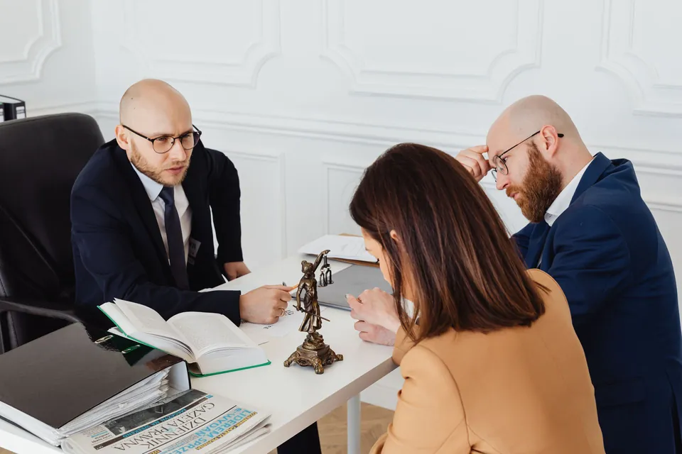 Advogado conversa com dois clientes sobre documentos