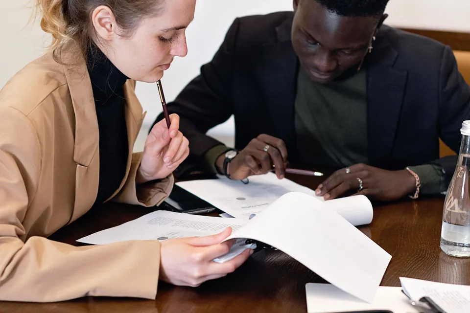 Profissional confere documentos com um cliente à mesa