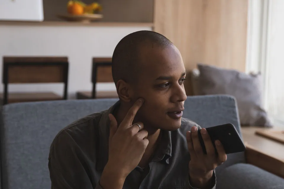 Homem confere o celular sentado no sofá de casa