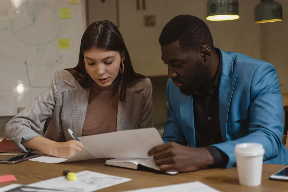 Profissional confere documentos com um cliente à mesa