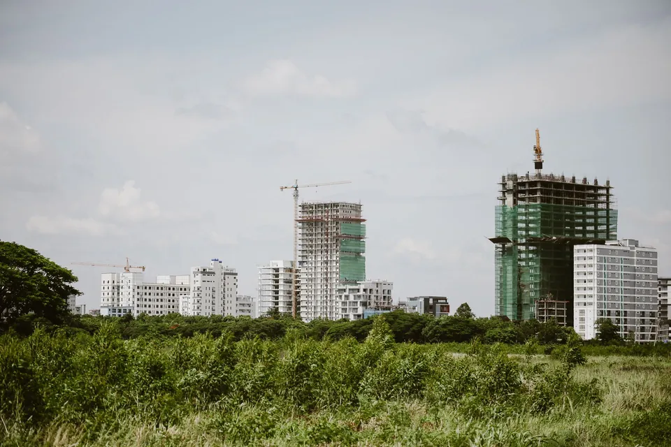 Prédio residencial em obra, com estrutura de concreto e guindastes
