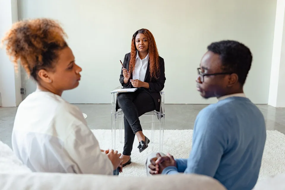 Mediadora conversa com uma mulher e um homem sentados frente a frente
