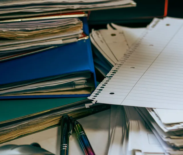 Pastas e documentos empilhados sobre a mesa