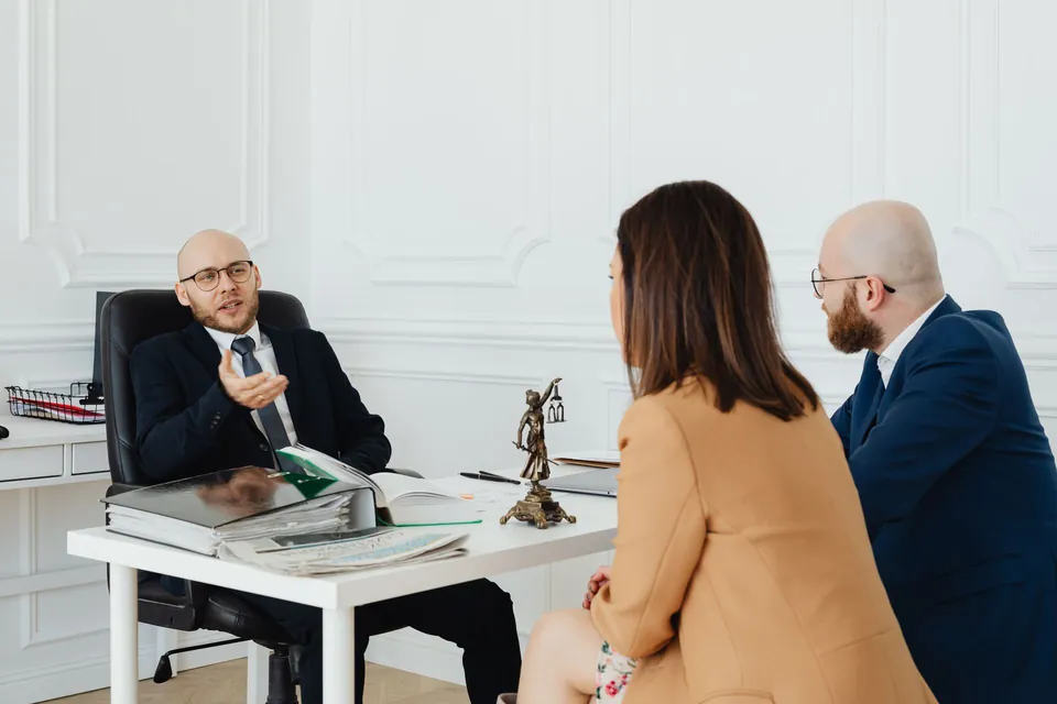 Advogado conversa com dois clientes sobre o processo