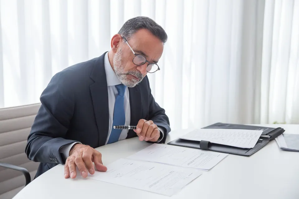 Homem confere um documento impresso na própria mesa