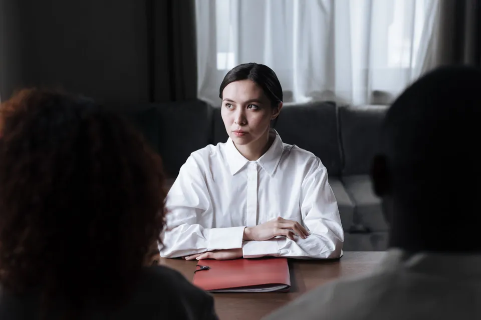 Advogada conversa com dois clientes à mesa do escritório