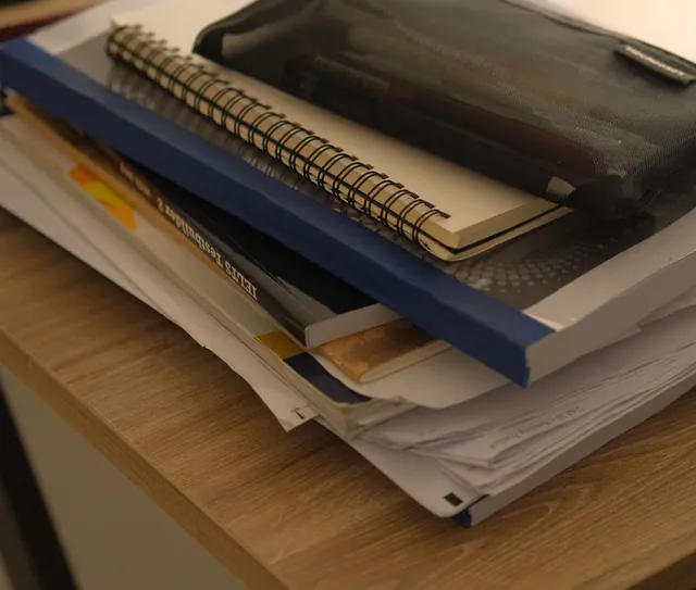 Cadernos e documentos empilhados sobre a mesa de madeira