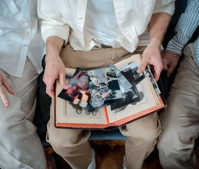 Mãos de uma família folheiam um álbum de fotos antigas