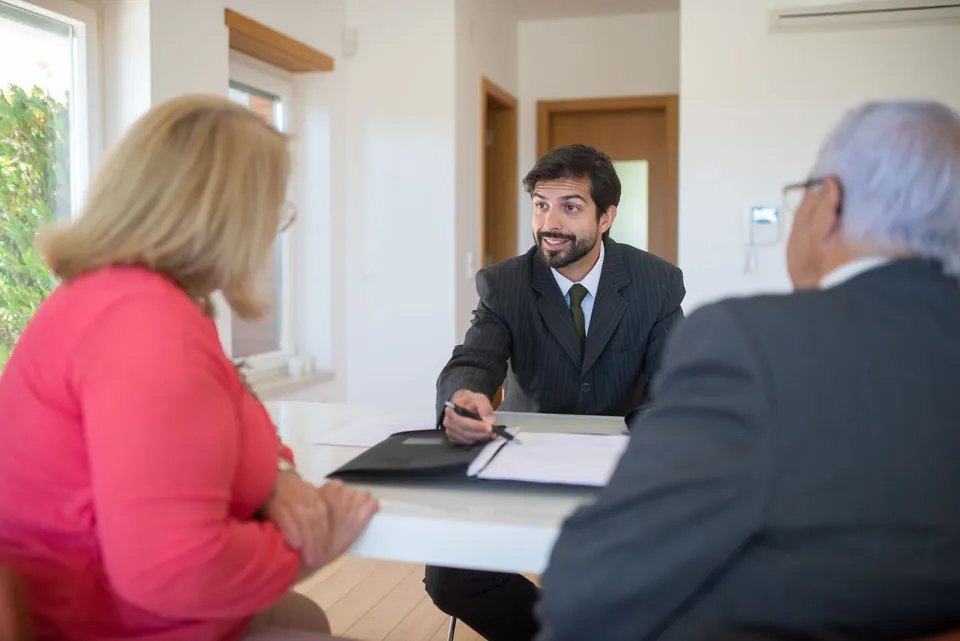 Profissional conversa com um casal de idosos sobre documentos