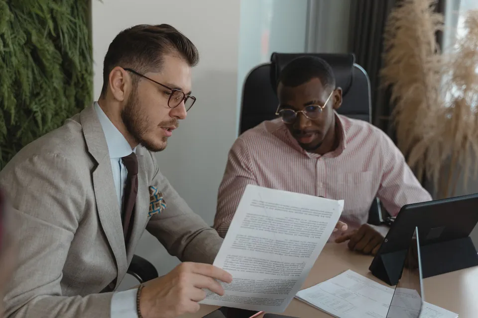 Profissional analisa um documento ao lado do cliente