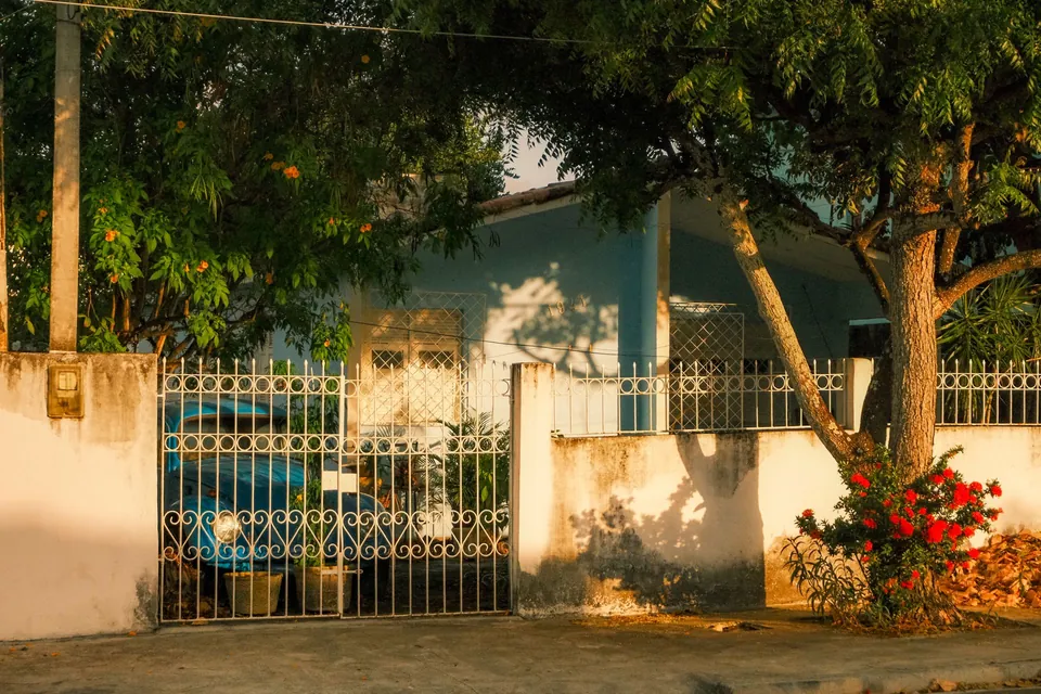 Fachada de uma casa com portão de ferro e jardim