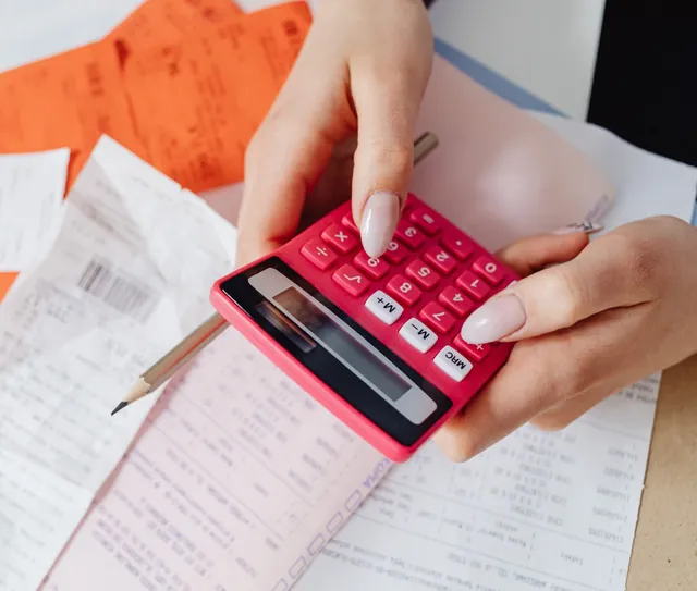Mãos usam uma calculadora sobre recibos e contas