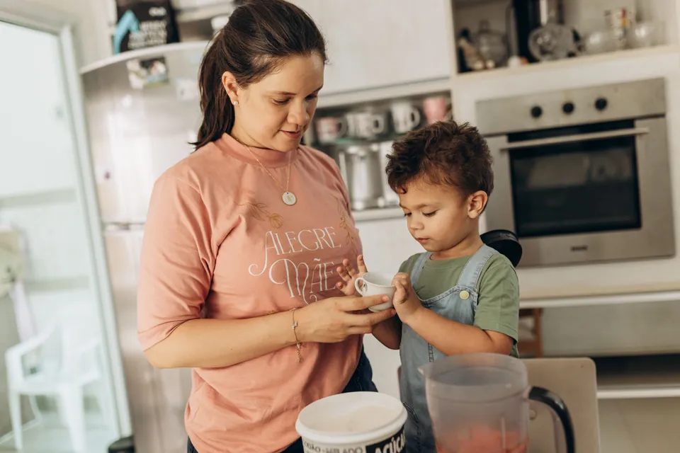 Mãe prepara um lanche com o filho pequeno na cozinha de casa