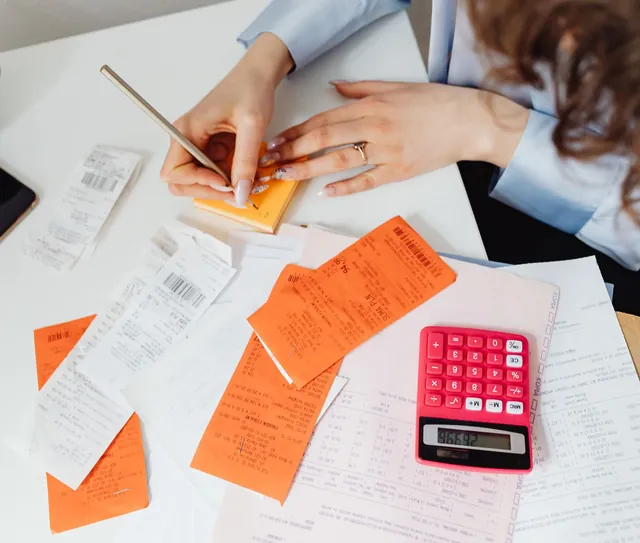 Recibos, anotações e calculadora sobre a mesa