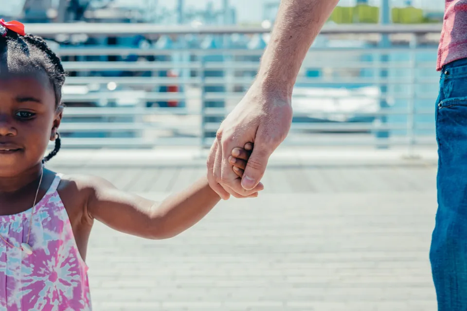 Menina de mãos dadas com um adulto
