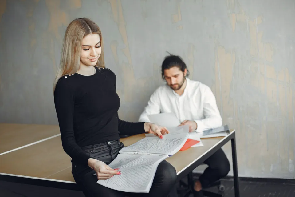 Duas pessoas conferem papéis de um imóvel sobre a mesa