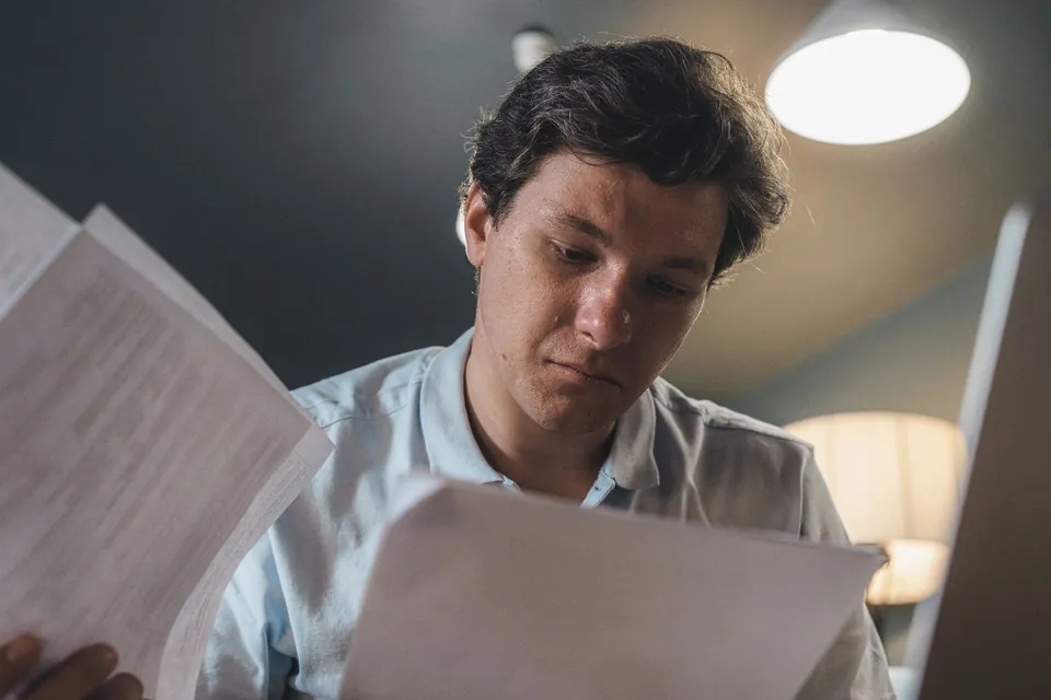 Homem confere papéis do trabalho em casa, à noite