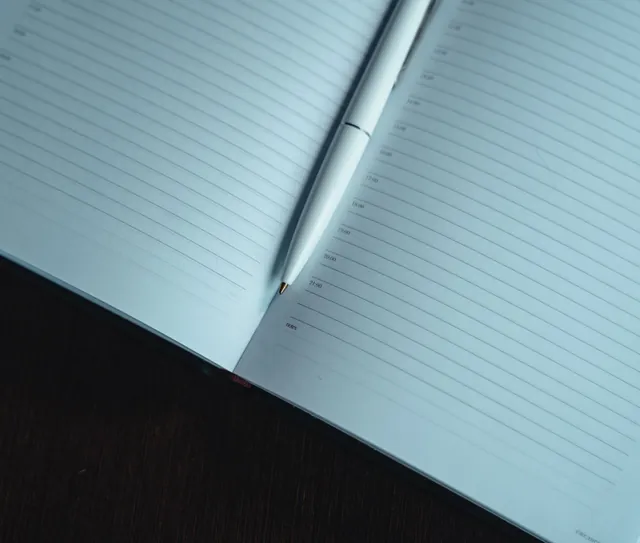 Caderno aberto e caneta sobre a mesa de madeira
