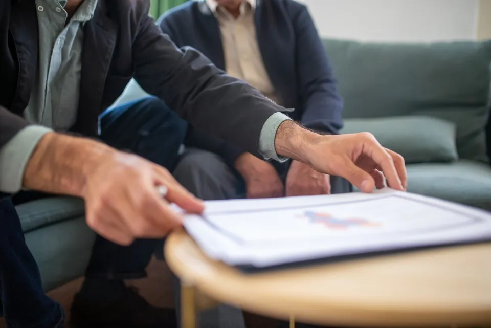 Duas pessoas conferem um contrato impresso à mesa