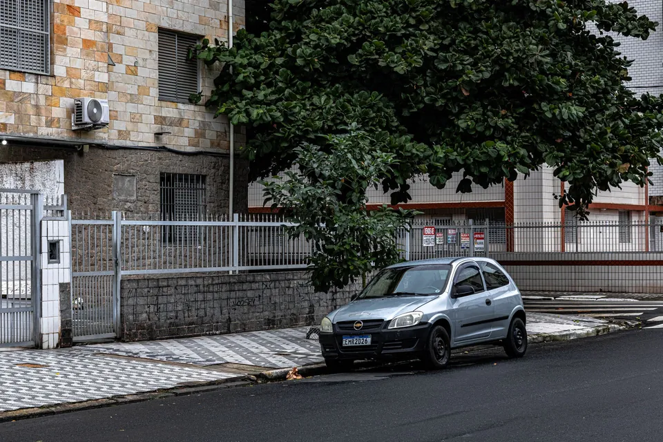 Rua residencial com um carro estacionado em frente às casas