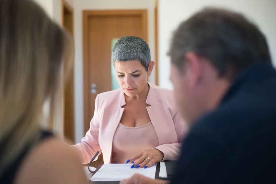 Profissional confere documentos com clientes durante o atendimento
