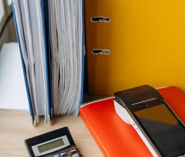 Pastas de documentos e calculadora sobre a mesa