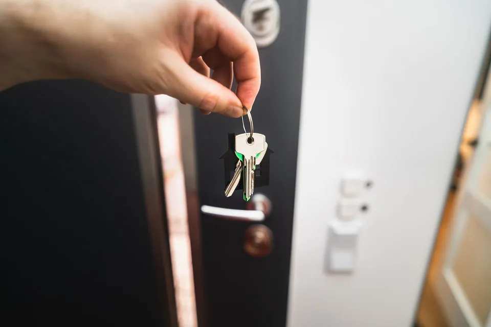 Mão coloca a chave na fechadura da porta