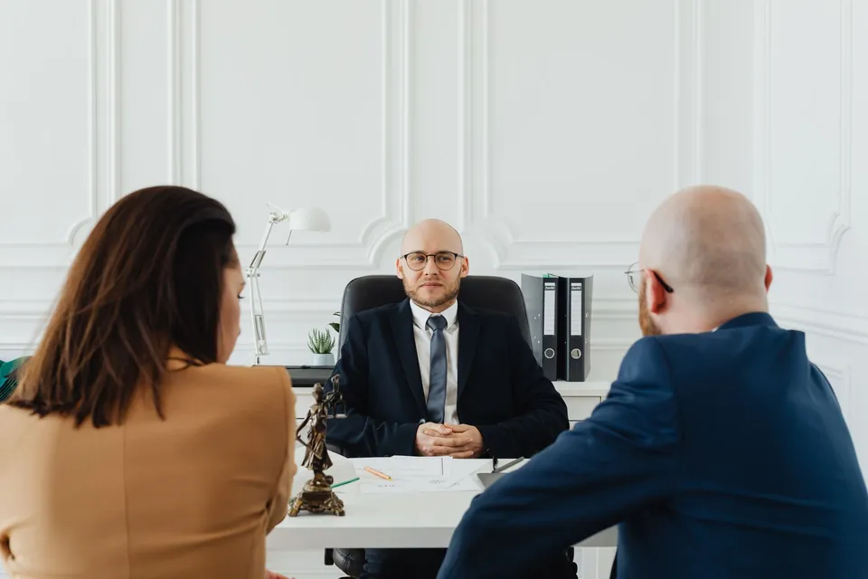 Advogado conversa com dois clientes sobre documentos