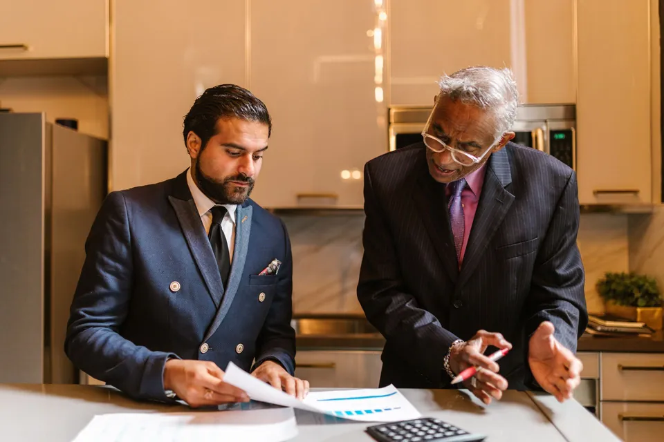 Duas pessoas analisam documentos financeiros na mesa