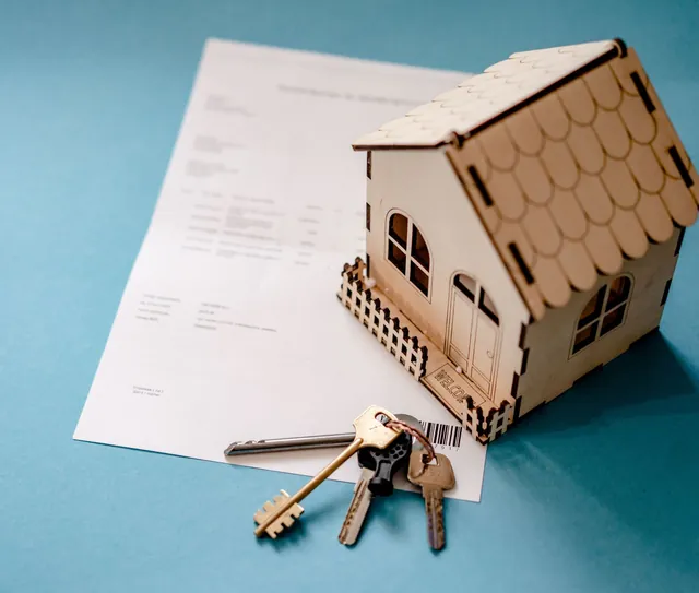 Casa em miniatura, um molho de chaves e um contrato sobre a mesa