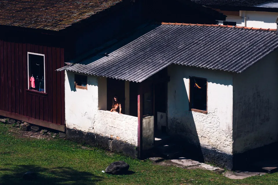 Casa simples de alvenaria com telhado de fibrocimento, em rua de bairro