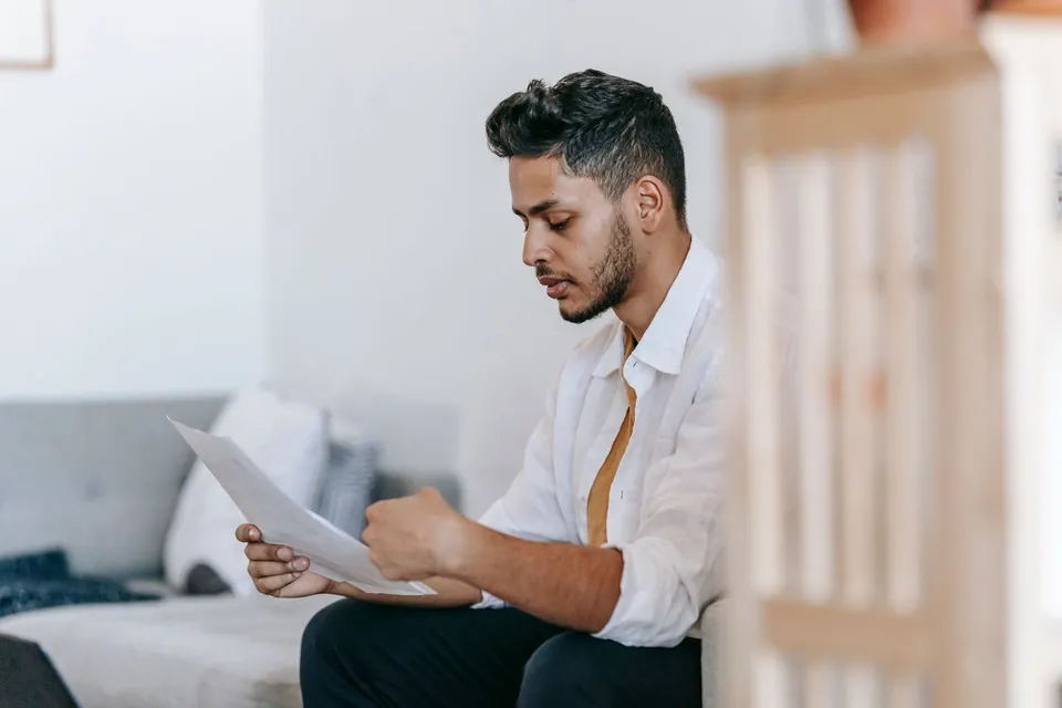 Homem lê com atenção as páginas de um contrato